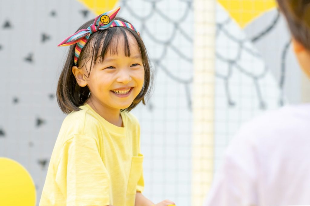 黄色い服を着た女の子が笑顔でこちらを向いている様子