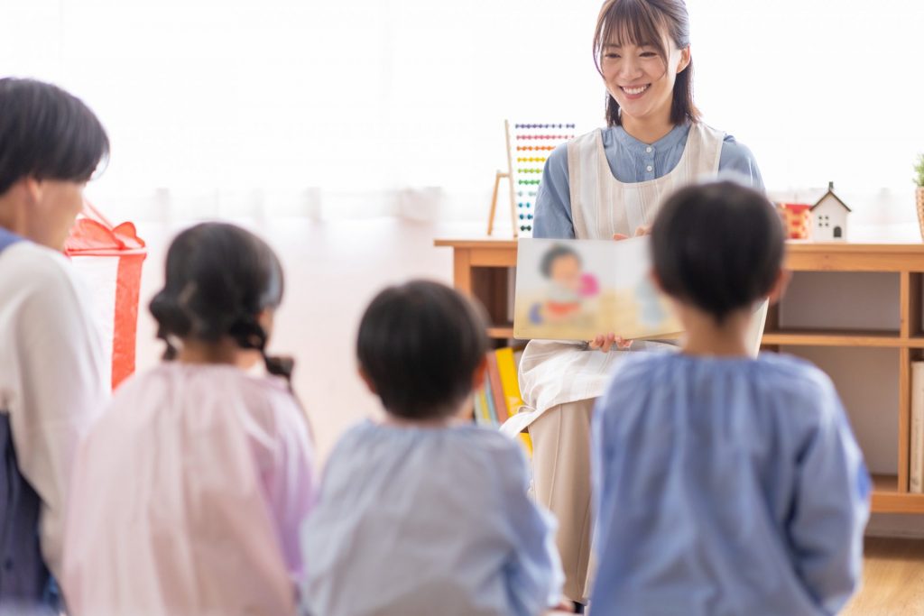 絵本を読んでいる先生とそれを聞いている子どもたち