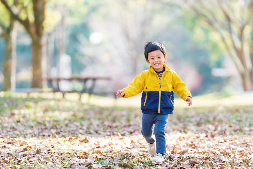 秋の季節に外をかけまわっている子ども
