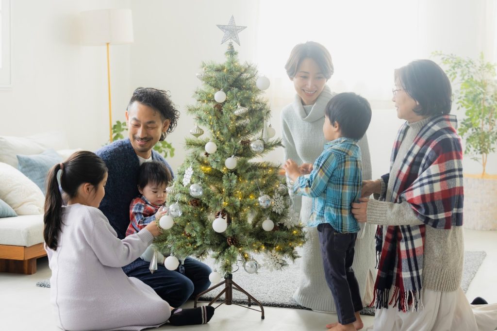 家族でクリスマスツリーの飾り付けをしている
