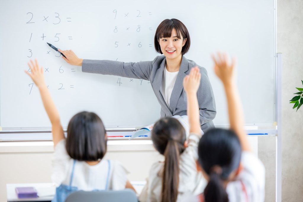 勉強でてを上げている子たちと勉強をし教えている先生