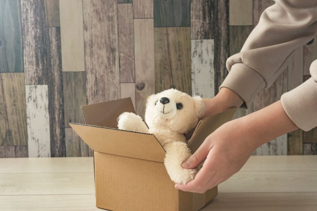 段ボールにクマのぬいぐるみを入れている様子の画像