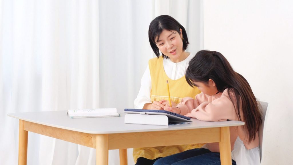 優しく勉強を教えているママと勉強している娘