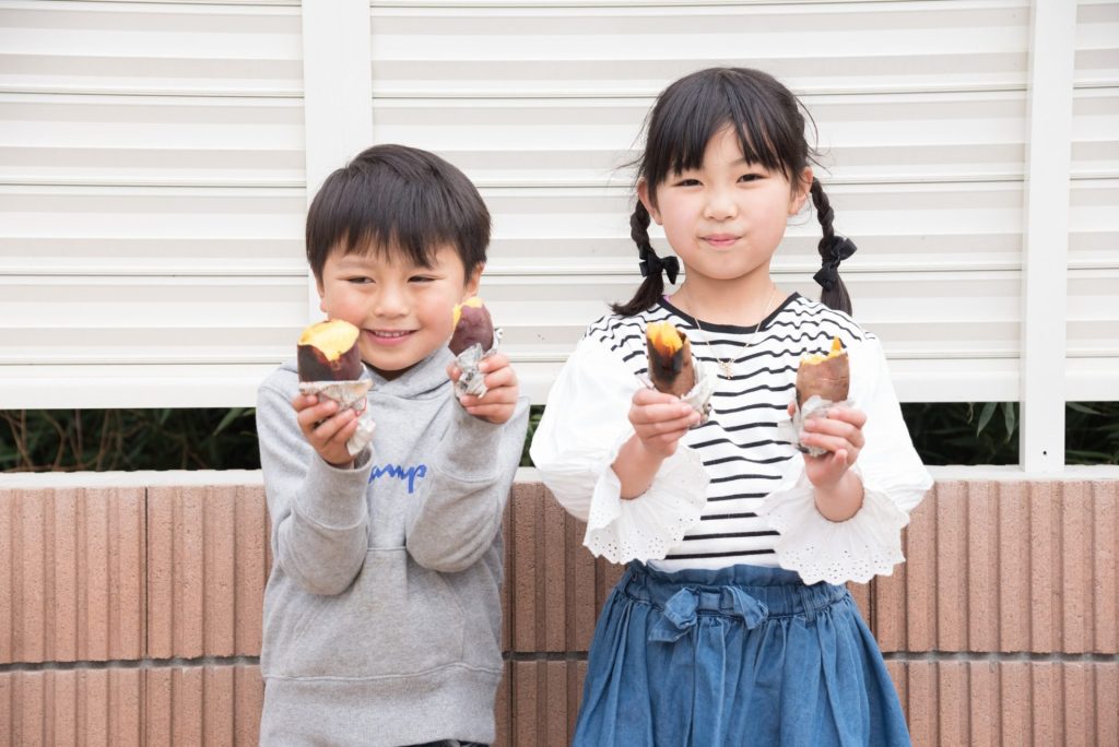 子供達が焼き芋を持って笑顔で写っている様子
